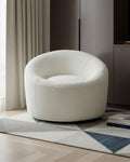 White textured armchair in a modern living room setting with a rug and books.