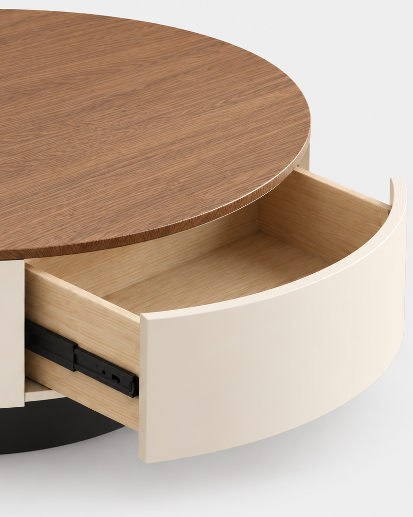 A close-up of a modern round coffee table with a dark brown wood top, a cream-colored side panel, and an open drawer showing a light wood interior.
