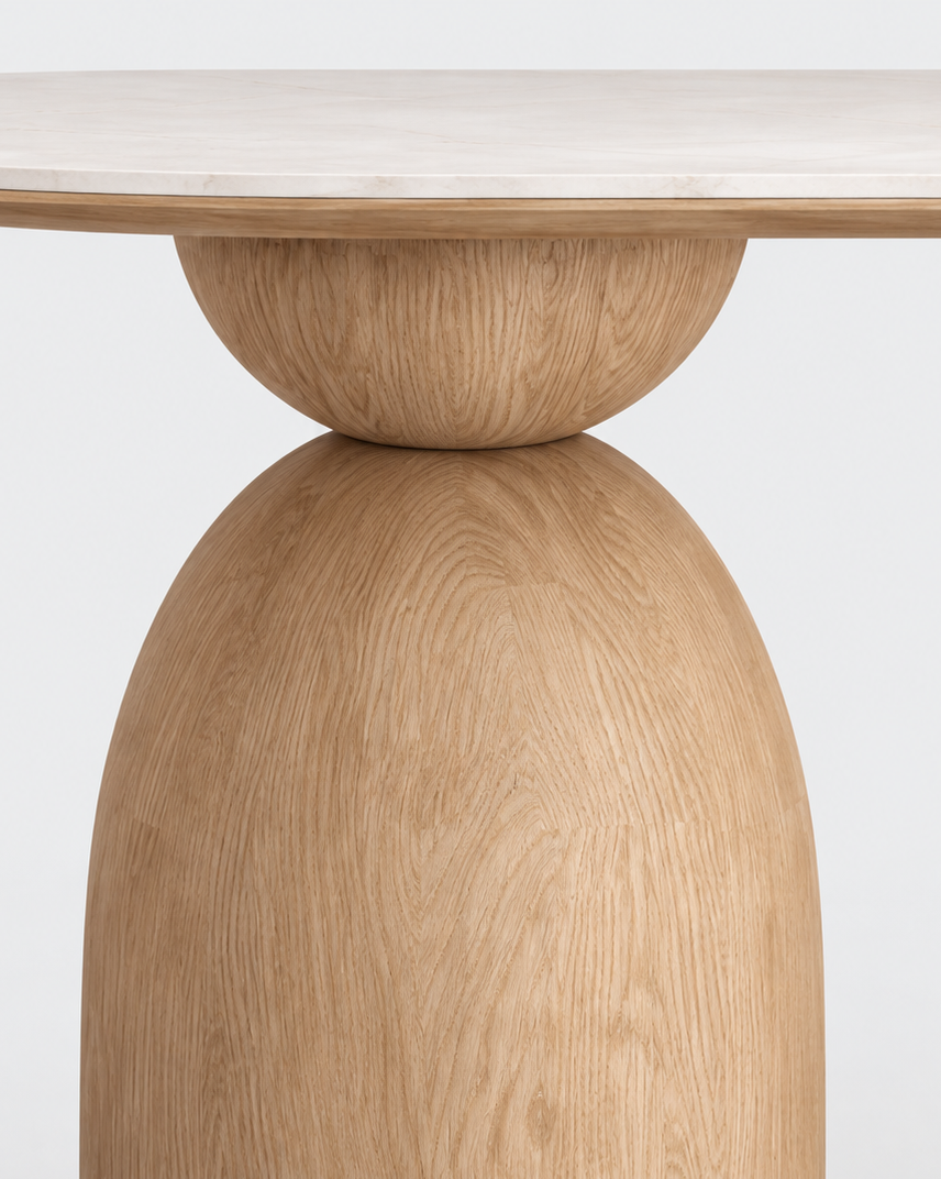 A close-up studio shot of a light oak wood pedestal dining table base with a matching round tabletop, showing the natural wood grain texture against a clean white background.