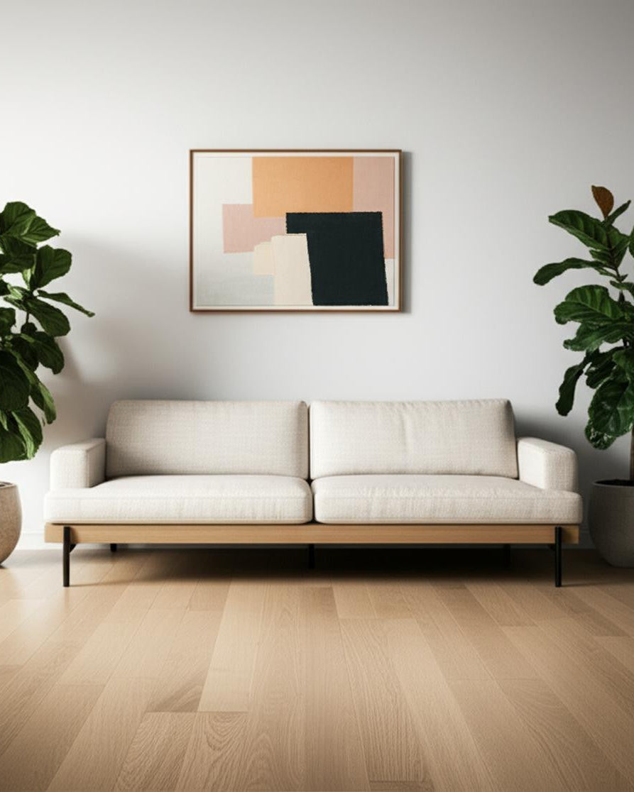 Modern living room with a white sofa, abstract art, and potted plants.